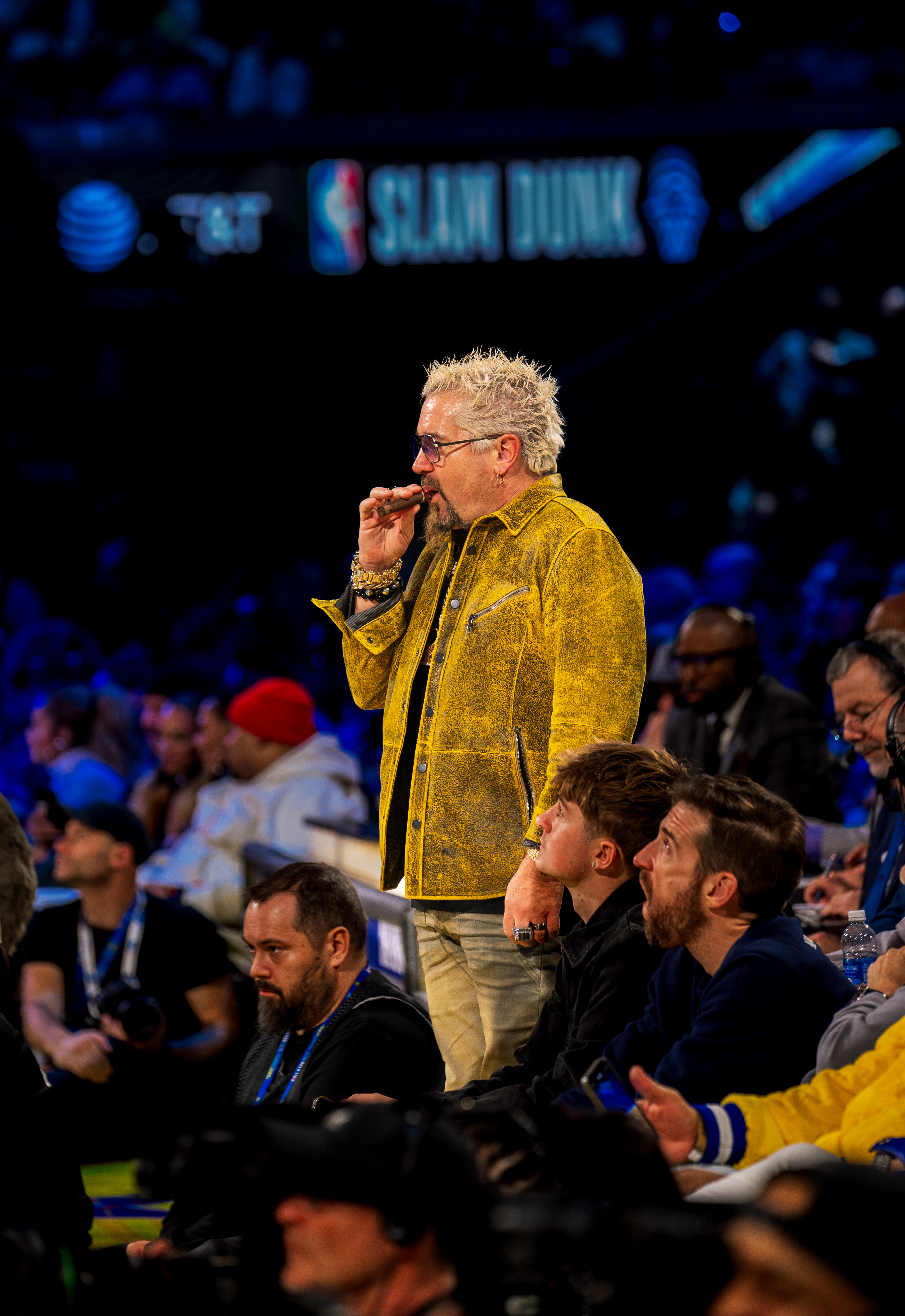 Guy Fieri in a yellow jacket watching the 2025 AT&T Slam Dunk Contest courtside at Chase Center